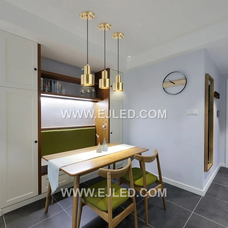 The MK0112 stands out with its tall, narrow cylindrical shade crafted from brass, featuring a distinct brushed brass finish. This clean-lined design offers a focused downlight, differentiating it from wider dome or cone pendants. - view 3