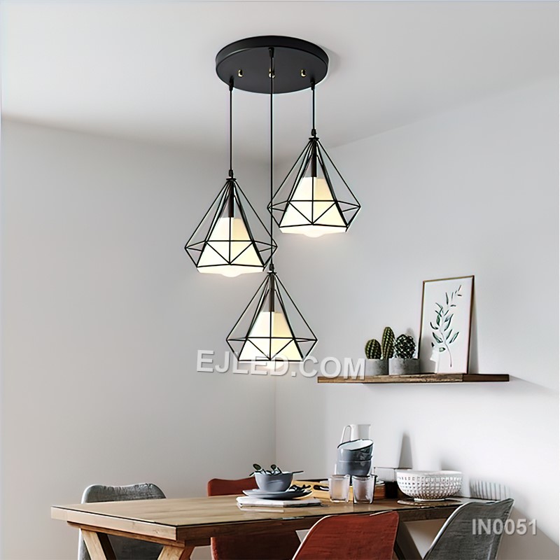 This IN0051 cluster pendant features three black iron diamond-shaped cages, each enclosing a spherical clear glass shade. Suspended at varying heights, it creates a visual centrepiece for rooms with higher ceilings.