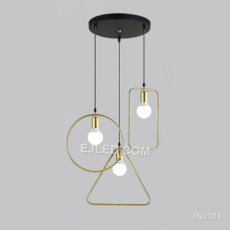 Three cylindrical brass cages form the IN0104 pendant light, each crafted from slender rods. These open frames, suspended from a linear bar, provide an exposed lamp design that diffuses light through the metallic structure. - view 2