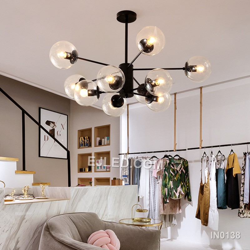 Distinct from simpler pendants, model IN0138 is an 8-light black steel chandelier, featuring a central hub with eight arms, each holding a clear spherical glass shade, offering widespread illumination. - view 2
