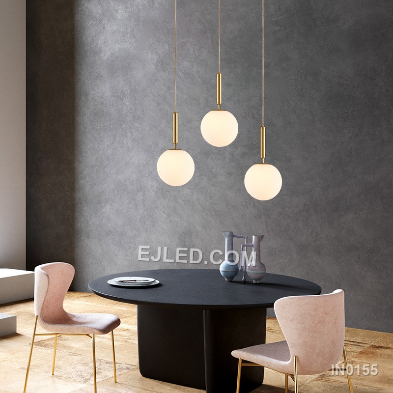 This single pendant light features a clear round glass shade encased by a polished brass frame. It suspends from a fabric-covered cord, casting a focused downlight and adding visual interest to dining areas, bedside tables, or compact reception spaces. - view 2