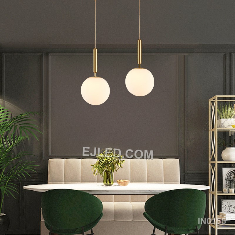 This single pendant light features a clear round glass shade encased by a polished brass frame. It suspends from a fabric-covered cord, casting a focused downlight and adding visual interest to dining areas, bedside tables, or compact reception spaces. - view 4