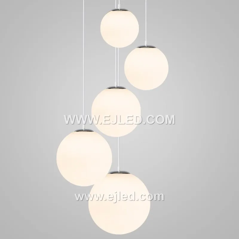 This multi-lamp pendant, model GL0020, features seven opaque white opal glass spheres suspended from a central chrome canopy. Designed to provide soft, diffused illumination, it creates a striking focal point for hospitality lobbies, stairwells, or residential dining areas. - view 3