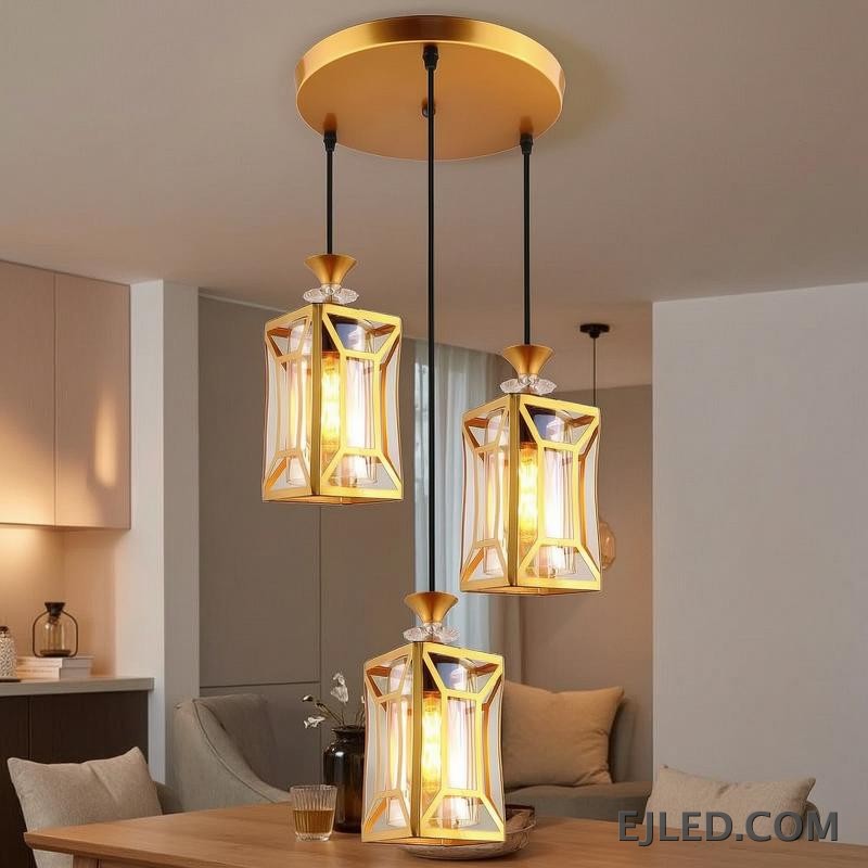 This fixture features three brass and clear glass pendant lights, each with an enclosed design, hanging from a single gold-finished canopy, casting a warm glow. - view 3