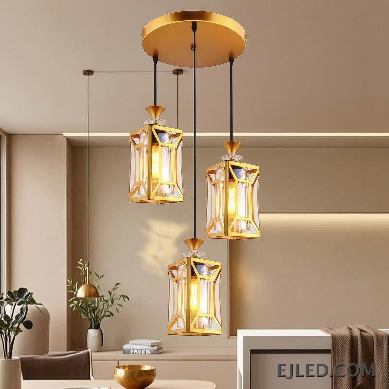 This fixture features three brass and clear glass pendant lights, each with an enclosed design, hanging from a single gold-finished canopy, casting a warm glow. - view 4