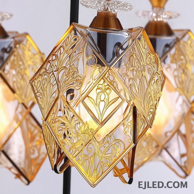 This three-light pendant fixture features gold-finished frames and clear glass panels forming distinct, double-box shades. Each shade encloses a single lamp, providing warm illumination from a round gold ceiling plate. - view 5