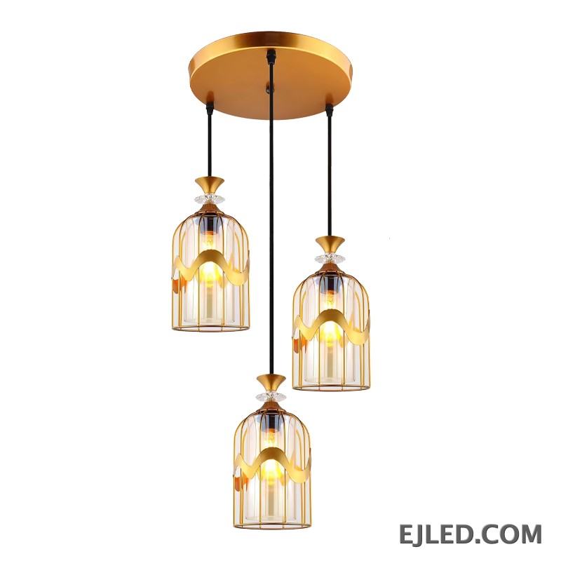 This pendant light features a clear glass cylindrical shade, capped with a sleek gold-finished brass element. It provides focused downward illumination from a single lamp, ideal for accent lighting or clustered arrangements.