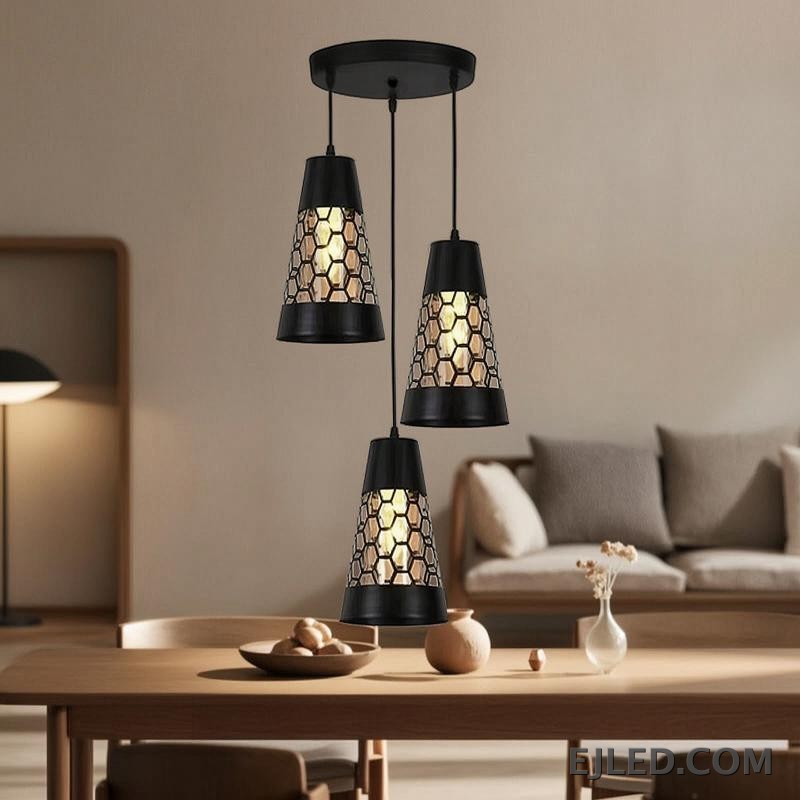 This triple pendant light features black iron conical shades. Each shade has a honeycomb cut-out pattern revealing a golden interior, suspended from a round black ceiling plate. - view 2