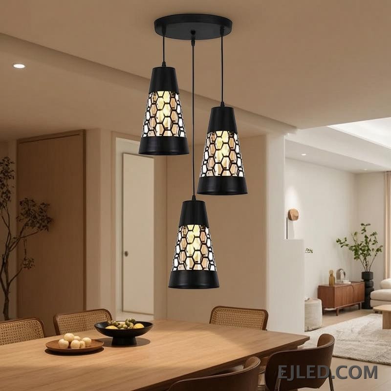 This triple pendant light features black iron conical shades. Each shade has a honeycomb cut-out pattern revealing a golden interior, suspended from a round black ceiling plate. - view 4