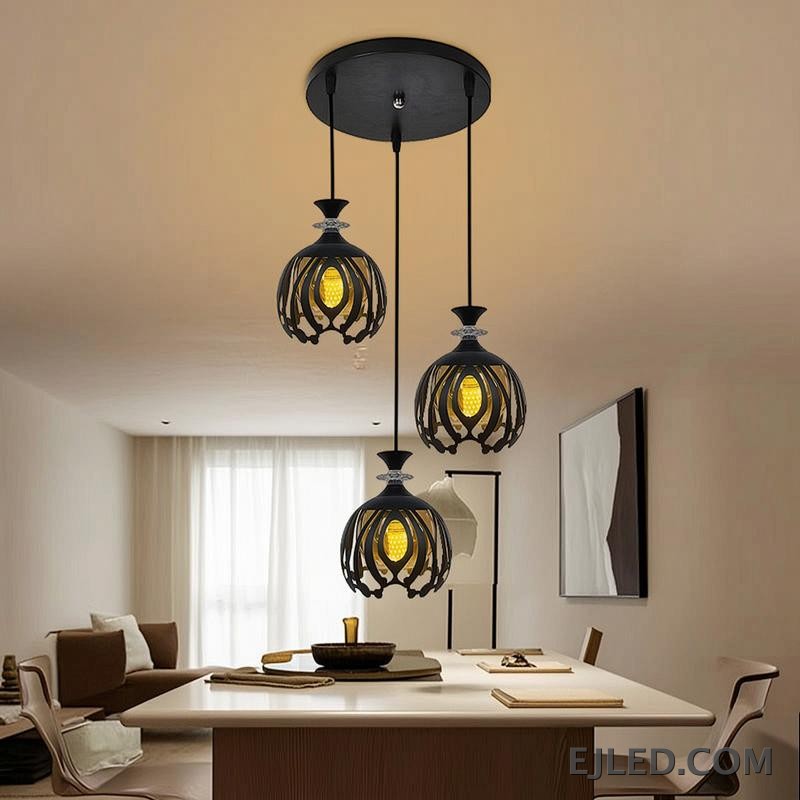 Esta lámpara colgante BS0012 cuenta con tres luces de hierro negro, cada una con una pantalla de jaula calada redonda que revela una luz interior dorada, rematada con un acento facetado transparente. - view 3