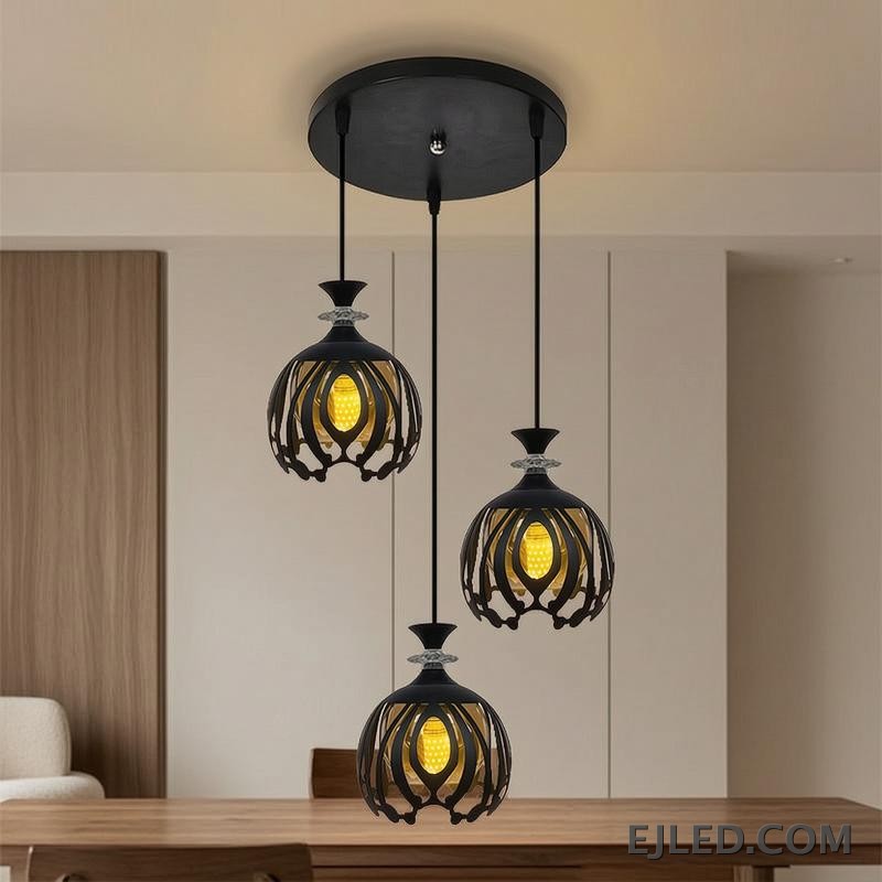Esta lámpara colgante BS0012 cuenta con tres luces de hierro negro, cada una con una pantalla de jaula calada redonda que revela una luz interior dorada, rematada con un acento facetado transparente. - view 4