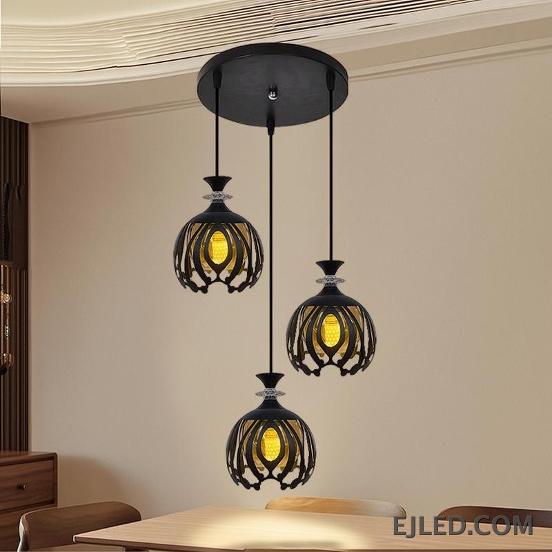 Esta lámpara colgante BS0012 cuenta con tres luces de hierro negro, cada una con una pantalla de jaula calada redonda que revela una luz interior dorada, rematada con un acento facetado transparente. - view 5