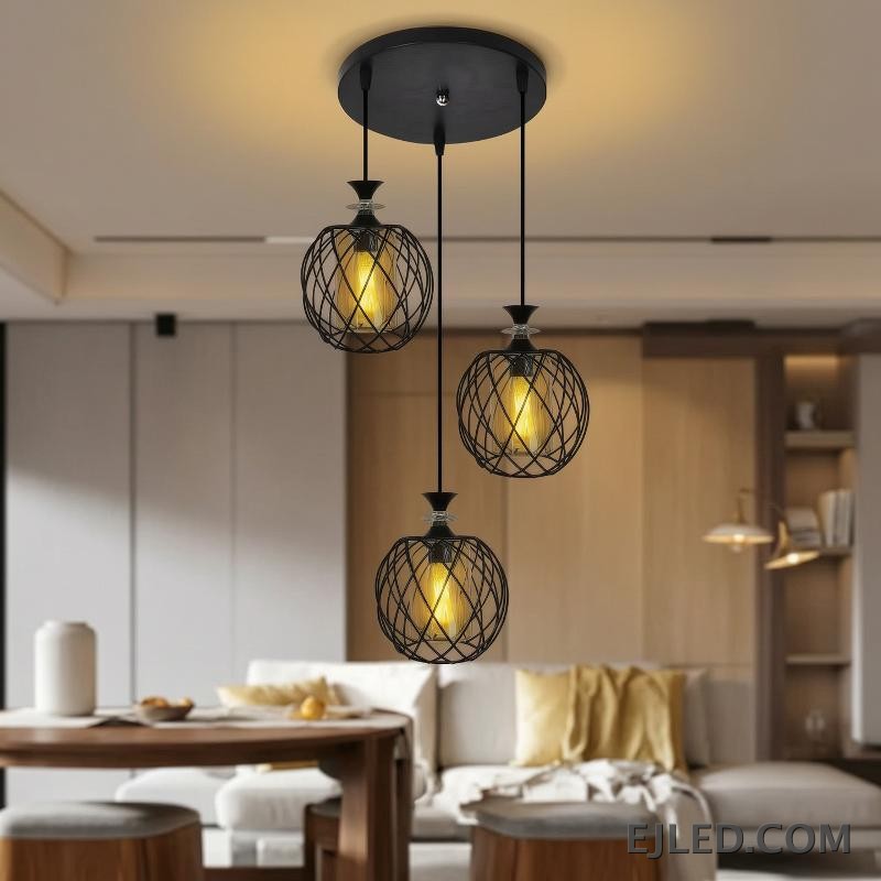 Esta lámpara colgante de múltiples luces cuenta con tres lámparas, cada una con una jaula de alambre de hierro negro que rodea un cilindro de vidrio ámbar, suspendidas de una base redonda negra de techo. - view 5