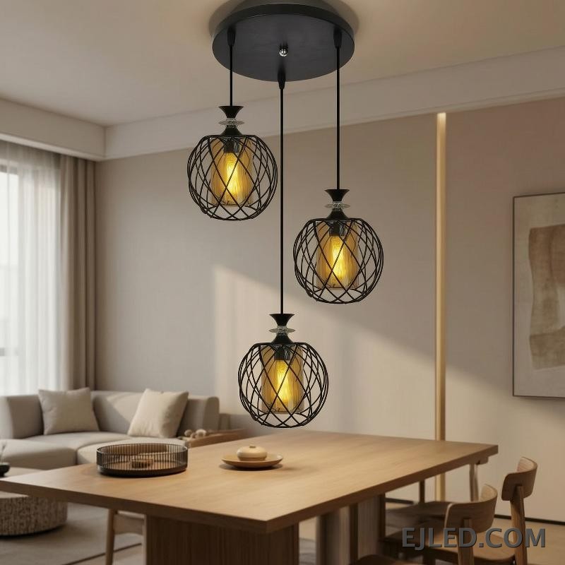 Esta lámpara colgante de múltiples luces cuenta con tres lámparas, cada una con una jaula de alambre de hierro negro que rodea un cilindro de vidrio ámbar, suspendidas de una base redonda negra de techo. - view 6
