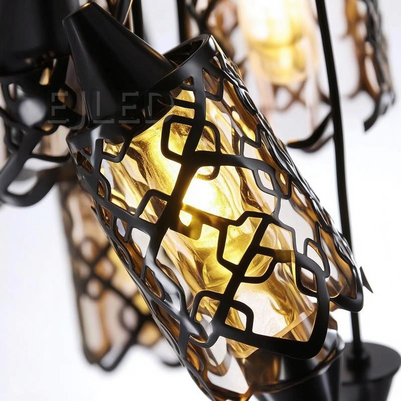 This three-light pendant features black iron cylindrical shades with an open geometric pattern over an inner amber-tinted enclosure. Each light hangs at a different length from a black circular ceiling plate, providing a warm, inviting glow. - view 5