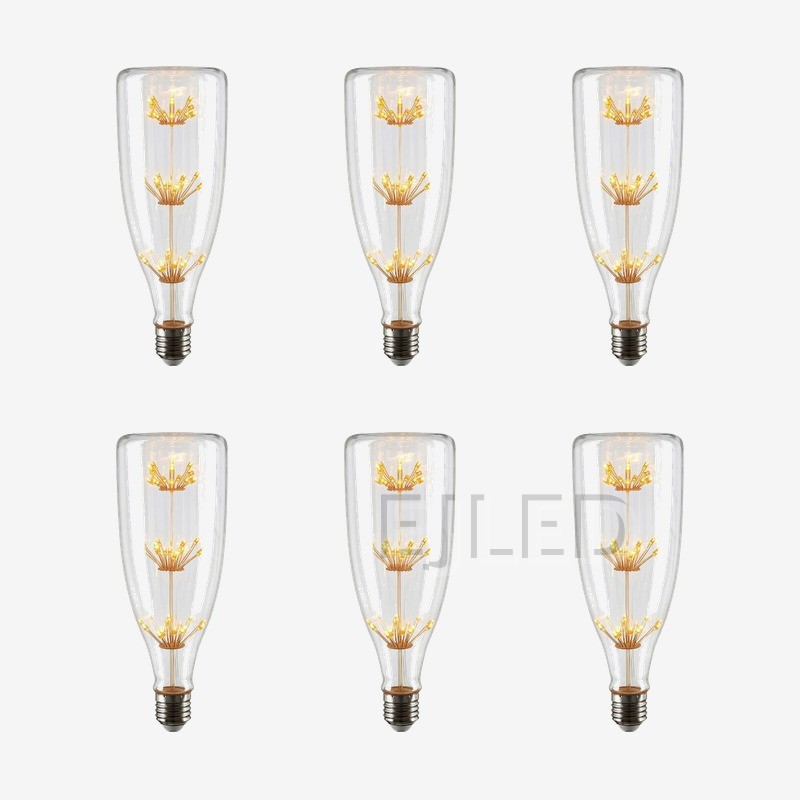 This clear glass starry LED bulb features a tall bottle shape and three vertical tiers of delicate firework style filaments connected to a standard screw base. - view 5