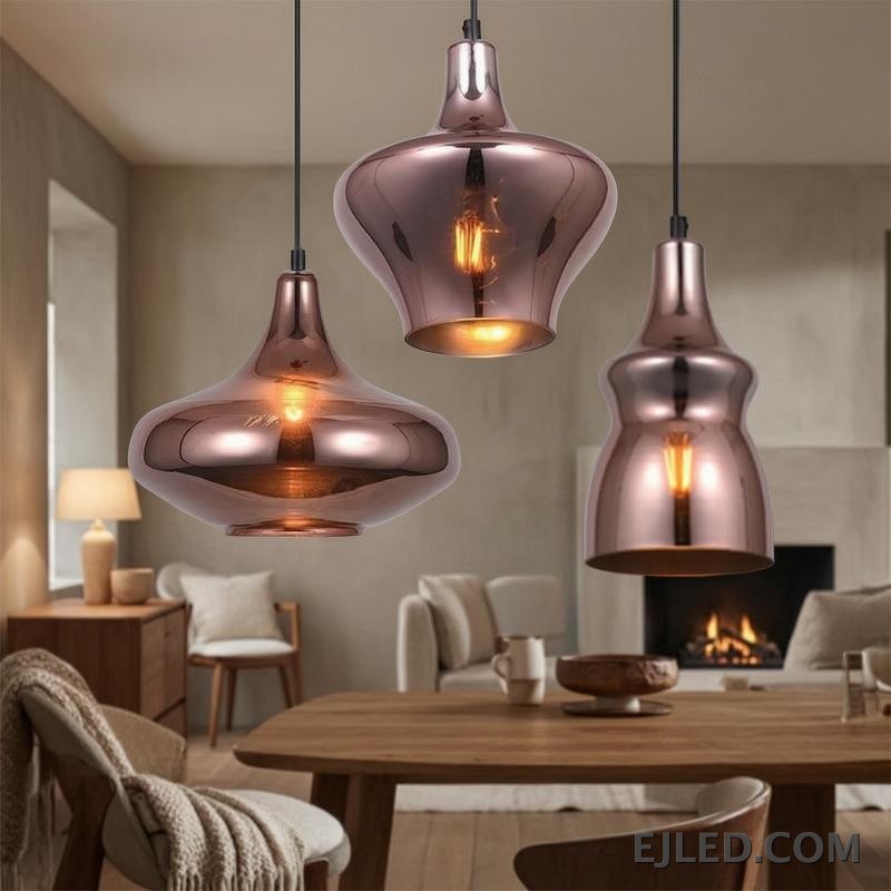 This collection features reflective copper-toned glass pendant lights in three distinct bell shapes. Each fixture houses a single bulb, providing warm, downward illumination. - view 5