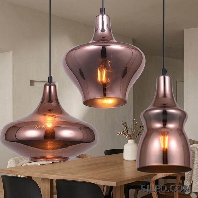 This collection features reflective copper-toned glass pendant lights in three distinct bell shapes. Each fixture houses a single bulb, providing warm, downward illumination. - view 6