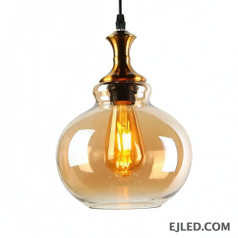 This glass pendant light features a spherical, amber-tinted shade that encloses a single exposed filament bulb. It hangs from a black suspension cord, complemented by a polished gold-finished metal cap.