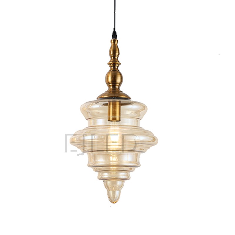 This distinctive amber glass pendant light features a sculpted shade suspended from an ornate brass finial. Its single lamp is enclosed within the translucent, bell-shaped glass, offering a warm glow for various interior settings. - view 3