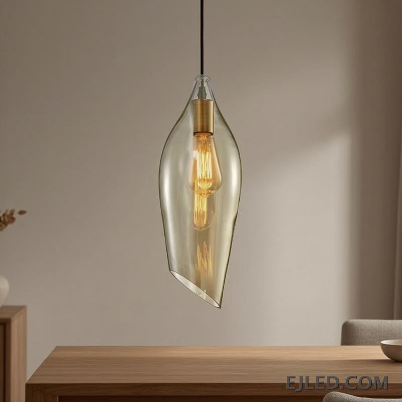 Esta lámpara colgante de cristal presenta una pantalla única asimétrica en forma de hoja con un tono ámbar cálido, que aloja una sola lámpara visible con portalámparas en tono latón. Cuelga de un cable negro sencillo y ofrece una base abierta para la difusión de la luz. - view 3