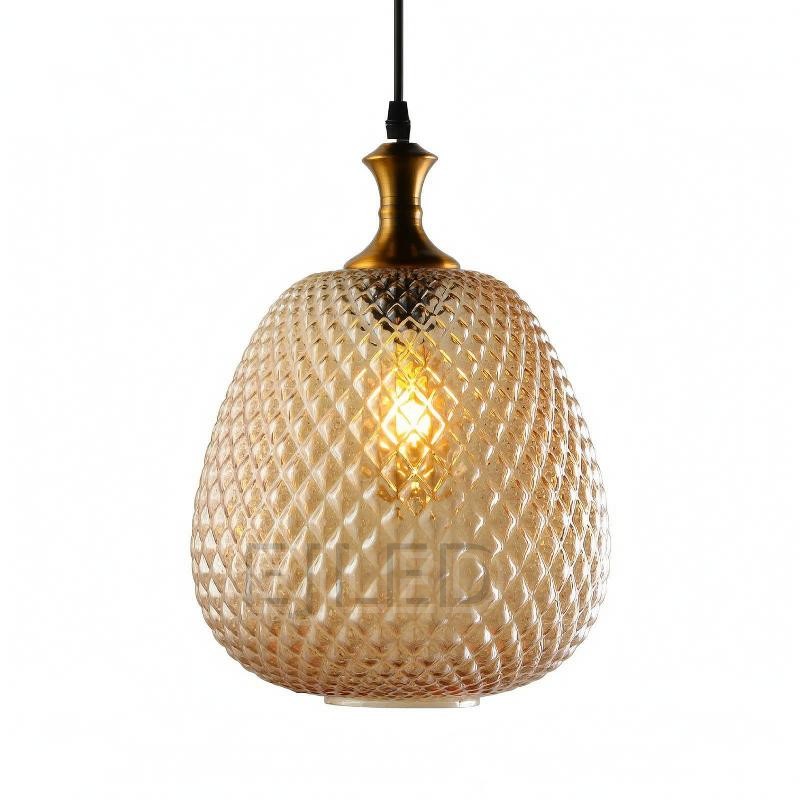 This amber textured glass pendant light features a bulbous diamond pattern shade paired with a metallic brass top and a black suspension cord.