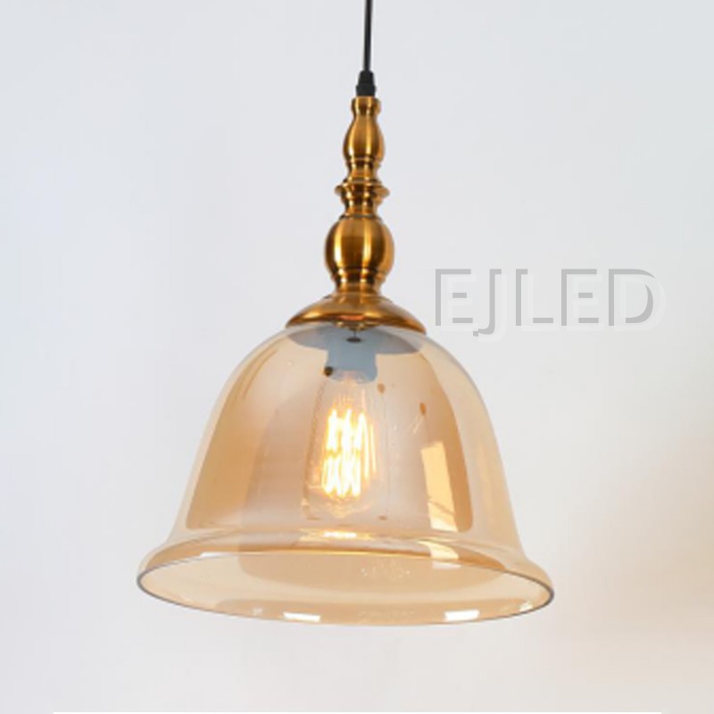 This pendant light features a bell-shaped amber glass shade suspended from an ornate brass-finished metal top. It uses one visible lamp for warm interior illumination. - view 2