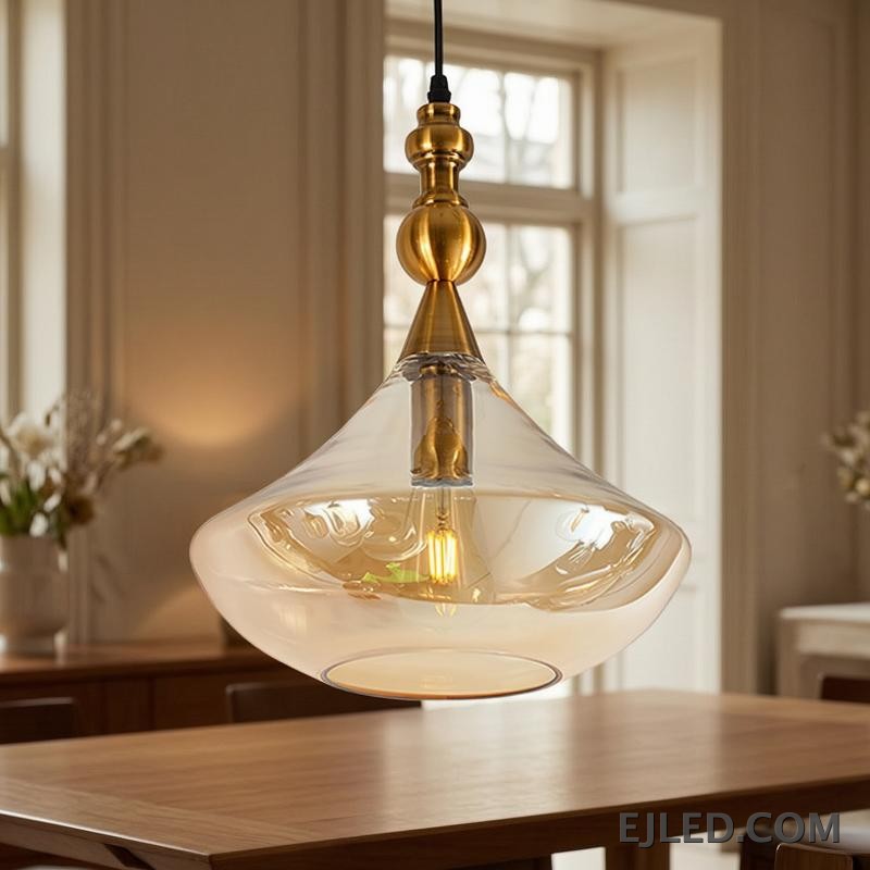 This glass bowl pendant light features a wide, shallow clear glass shade complemented by a brushed brass rim and ceiling canopy. It projects diffused, ambient light from a single lamp, hanging from a fabric-covered cord. - view 2
