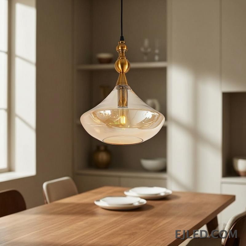 This glass bowl pendant light features a wide, shallow clear glass shade complemented by a brushed brass rim and ceiling canopy. It projects diffused, ambient light from a single lamp, hanging from a fabric-covered cord. - view 3