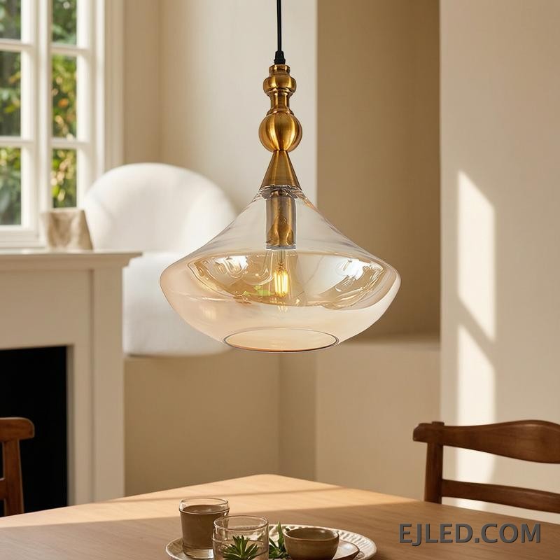 This glass bowl pendant light features a wide, shallow clear glass shade complemented by a brushed brass rim and ceiling canopy. It projects diffused, ambient light from a single lamp, hanging from a fabric-covered cord. - view 6