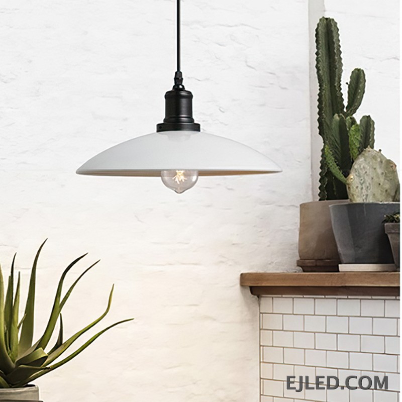 This iron dome pendant lamp features a matte black exterior shade and a reflective interior. It suspends from a black cord and illuminates with a single, exposed bulb. The fixture has a dark, textured finish on its connecting hardware. - view 4