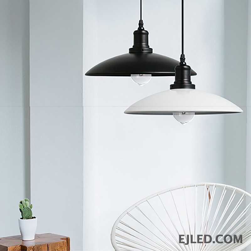 This iron dome pendant lamp features a matte black exterior shade and a reflective interior. It suspends from a black cord and illuminates with a single, exposed bulb. The fixture has a dark, textured finish on its connecting hardware. - view 5