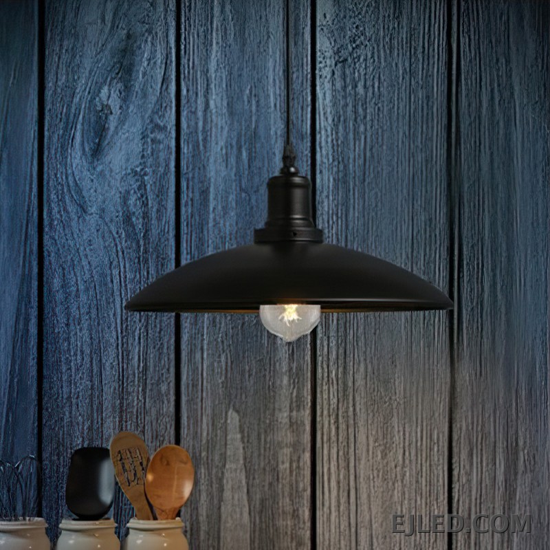 This iron dome pendant lamp features a matte black exterior shade and a reflective interior. It suspends from a black cord and illuminates with a single, exposed bulb. The fixture has a dark, textured finish on its connecting hardware. - view 6
