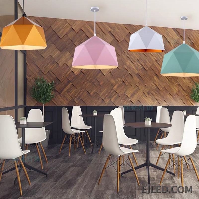 This steel pendant light features a multi-faceted geometric shade. It has a matte black exterior finish and a contrasting warm orange interior, providing downward illumination. - view 3