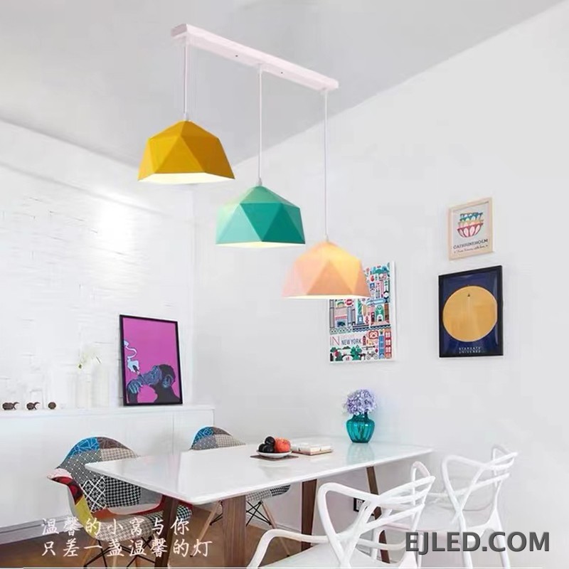 This steel pendant light features a multi-faceted geometric shade. It has a matte black exterior finish and a contrasting warm orange interior, providing downward illumination. - view 4