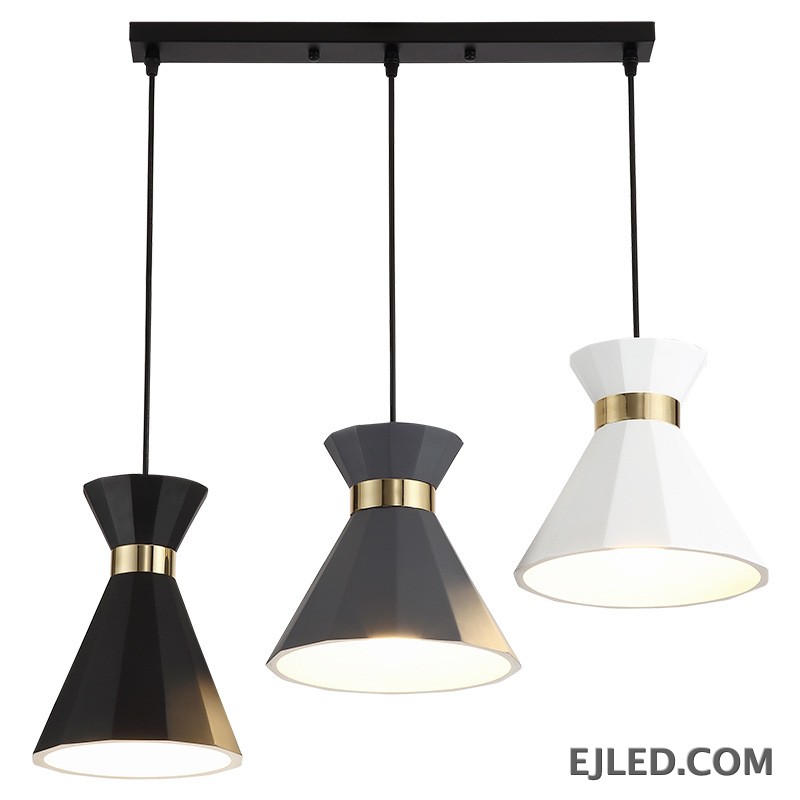 This fixture features three faceted aluminum pendant lamps in black, gray, and white, each accented with a gold-colored band. They hang from a black linear canopy, providing downward light from their open cone shades.