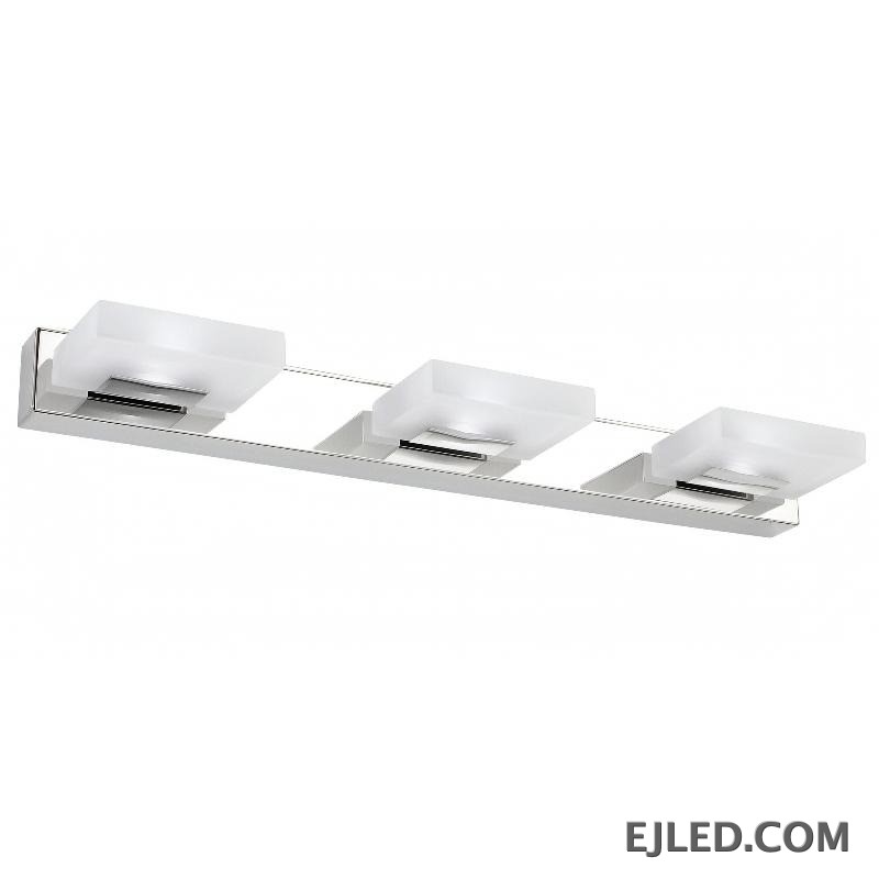A vertical chrome-finished stainless steel mirror lamp features three individual rectangular light heads, each with an opaque white acrylic diffuser. Its clean, upright silhouette provides focused illumination for task areas in various settings.