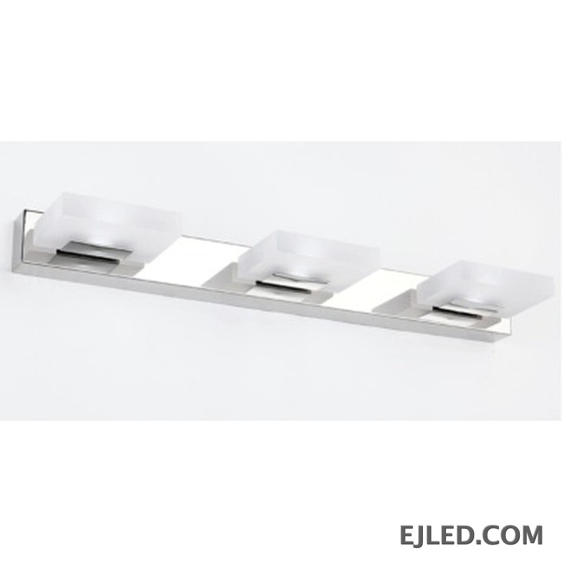 Una lámpara de espejo vertical de acero inoxidable con acabado cromado presenta tres cabezales de luz rectangulares individuales, cada uno con un difusor de acrílico blanco opaco. Su silueta limpia y vertical proporciona iluminación enfocada para áreas de trabajo en diversos entornos. - view 2