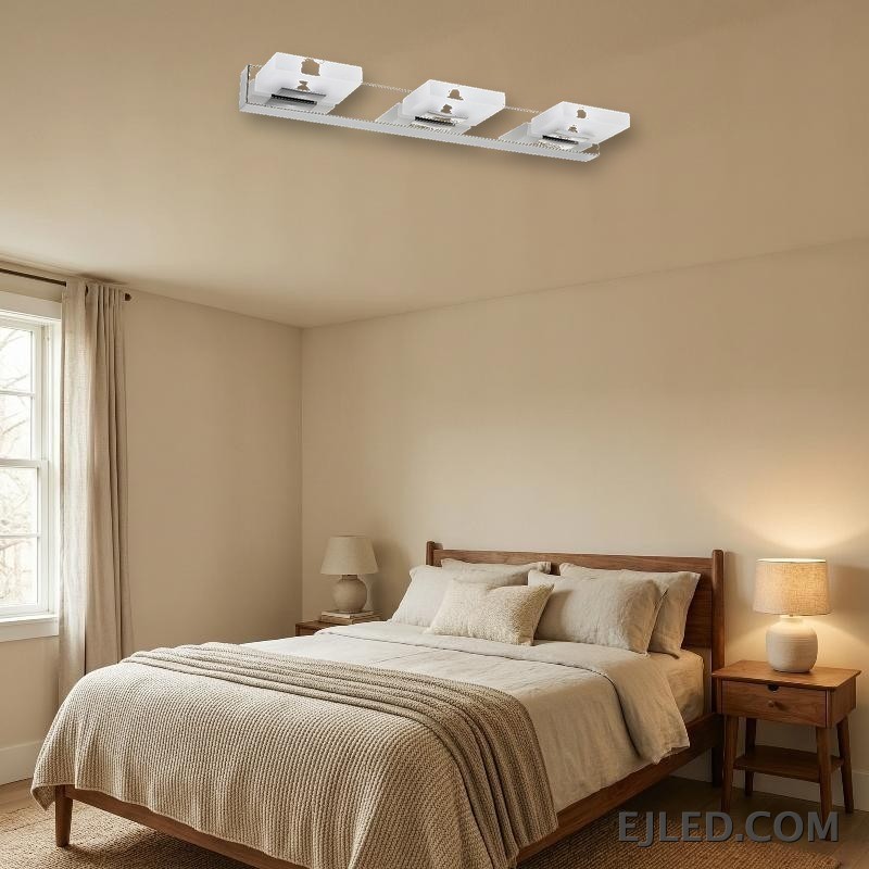 Una lámpara de espejo vertical de acero inoxidable con acabado cromado presenta tres cabezales de luz rectangulares individuales, cada uno con un difusor de acrílico blanco opaco. Su silueta limpia y vertical proporciona iluminación enfocada para áreas de trabajo en diversos entornos. - view 5