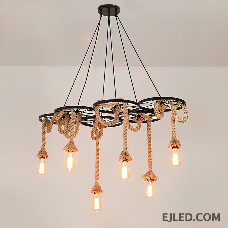 Este candelabro multiluz de cuerda de cáñamo presenta seis marcos de rueda de hierro, cada uno suspendiendo una bombilla expuesta. El diseño combina hierro robusto con elementos naturales de cuerda, creando una estética industrial para espacios comerciales. - view 2