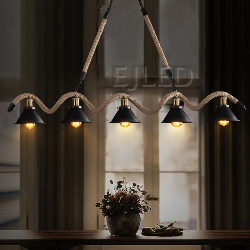 This linear pendant light features five black bell shades suspended along a thick woven hemp rope and metal chain assembly from a rectangular ceiling canopy. - view 3