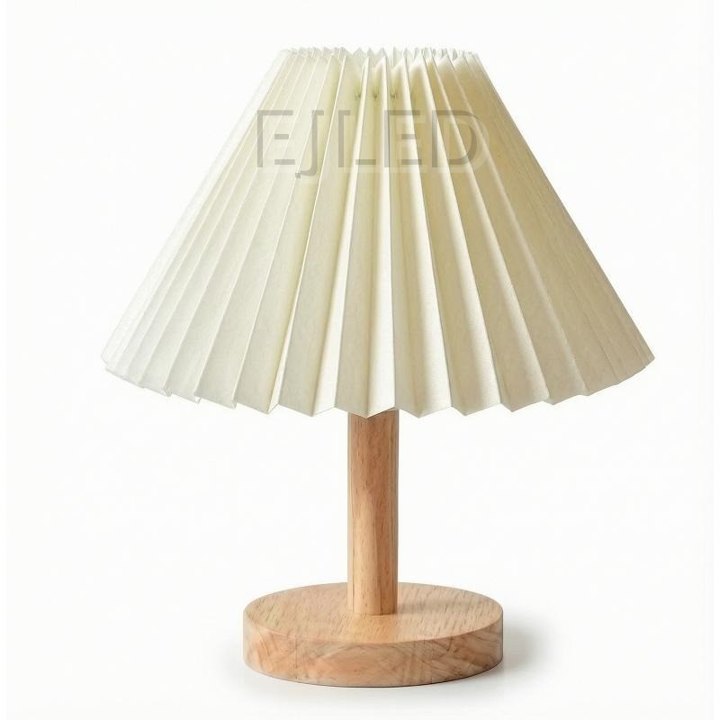 This wooden base table lamp features an off white pleated fabric shade supported by a natural wood stem and round wooden base.