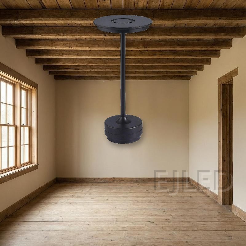 This black metal table lamp features a slim vertical stem connecting a flat circular top shade to a weighted round base. It provides portable cordless illumination. - view 5