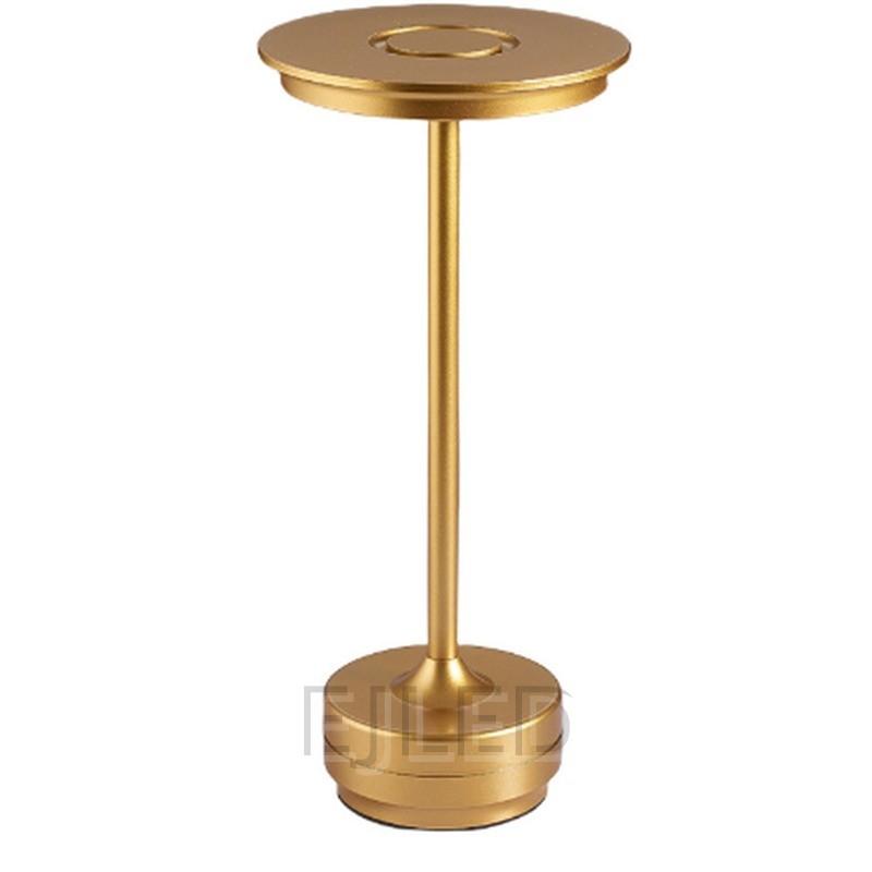 This minimalist metal table lamp features a solid round base, a slender vertical stem, and a flat circular top shade in a uniform gold finish. - view 2
