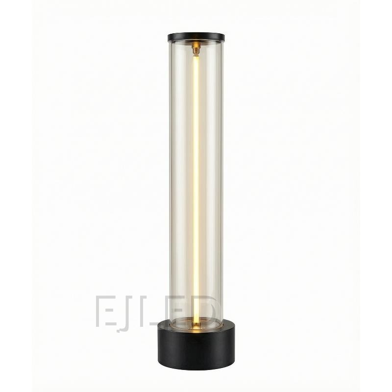 This cylindrical glass table lamp features a glowing central light tube mounted on a heavy black metal base with matching top trim.