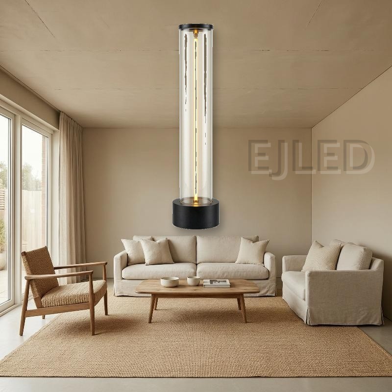This cylindrical glass table lamp features a glowing central light tube mounted on a heavy black metal base with matching top trim. - view 5
