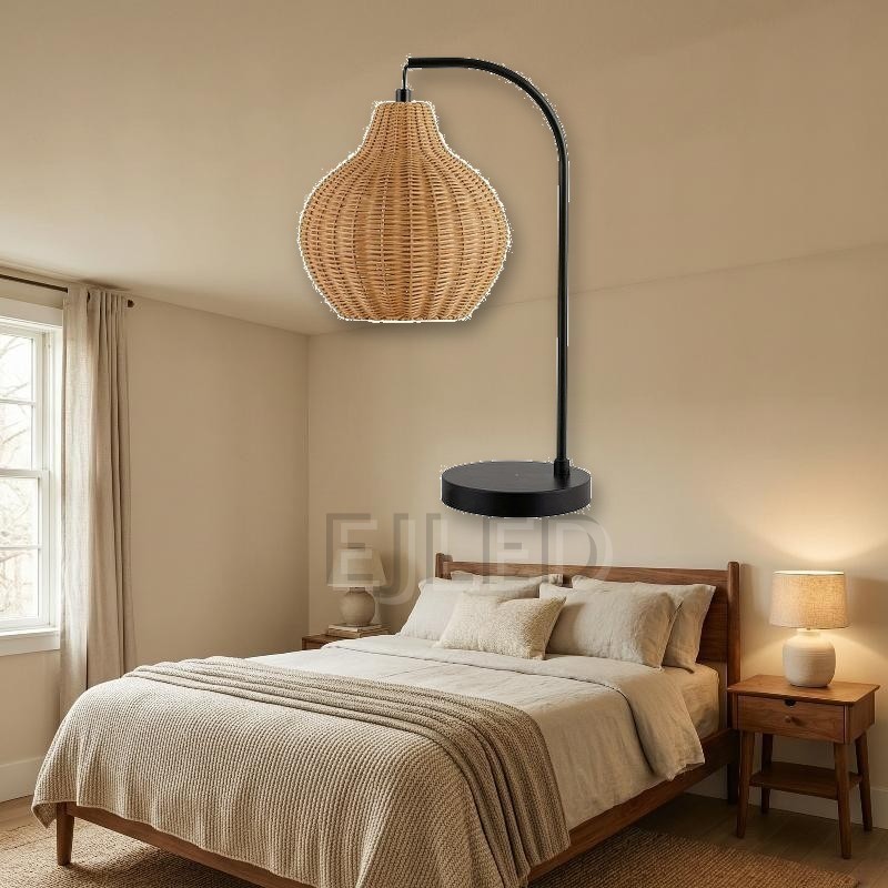 This table lamp features a curved black metal arm holding a woven rattan shade with an open bottom, mounted on a flat round base. - view 5