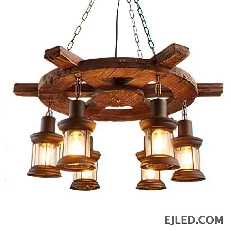 This wooden chandelier features a dark, rustic wagon wheel design with a 75cm diameter. Six clear glass lantern-style lights hang, offering an enclosed yet visible light source.