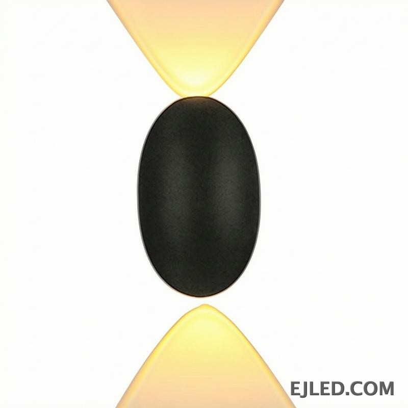 This black plastic wall light features a rounded rectangular front face and a diffused light output. It casts a soft, ambient glow upwards, downwards, and slightly forward, suitable for subtle accent illumination.