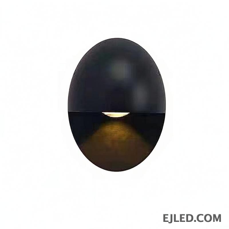 This black oval aluminum wall sconce projects a soft, downward light. Its distinctive design features a concealed light source within the lower half, providing indirect illumination.
